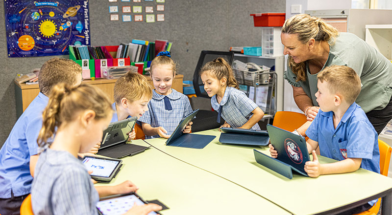 Teacher helping students at Holy Family Primary Luddenham