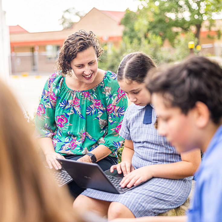 Teacher helping student at Holy Family Primary Luddenham